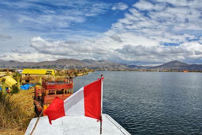 Scenic view of flag by lake against sky