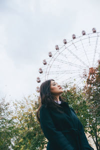 Young woman looking at camera against sky