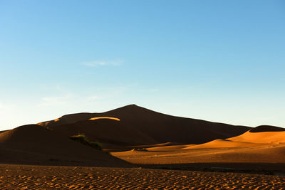 Scenic view of desert against clear blue sky