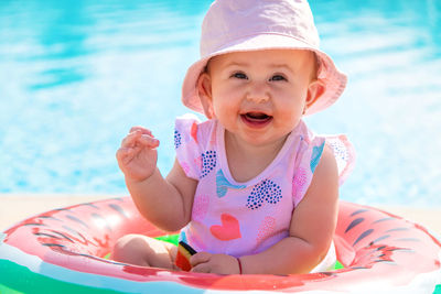 Portrait of smiling girl wearing hat sitting in swimming pool