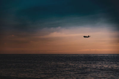 Silhouette of an airplane over the sea in evening twilight. airplane on the background of a seascape