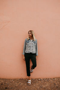 Portrait of young woman standing against wall