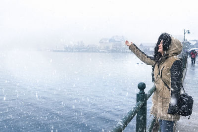 Woman standing by frozen lake against clear sky during winter