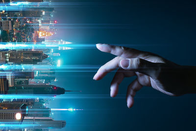 Digital composite image hand reaching towards illuminated city