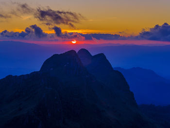 Scenic view of mountains against dramatic sky during sunset