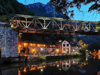 Illuminated bridge over river against sky at night