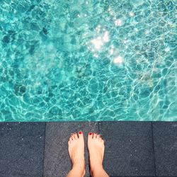 Low section of woman standing by swimming pool