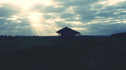 House on field against sky at sunset