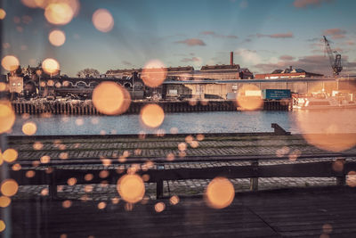 Illuminated bridge over river at dusk