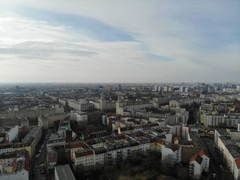 High angle view of city buildings against cloudy sky