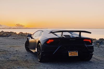 Car on beach against clear sky during sunset