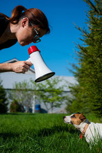 Woman with dog on field against sky