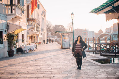 Full length portrait of woman against sky in city