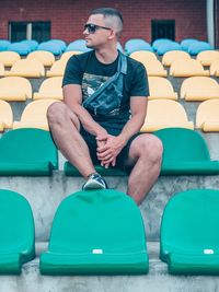 Full length of young man sitting on chair at stadium