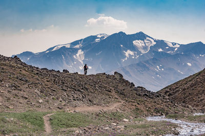 Rear view of man riding bicycle on mountains against sky