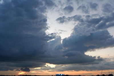 Low angle view of sunlight streaming through clouds during sunset