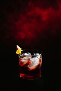 Close up of negroni cocktail in tumbler glass with dark red nebula background