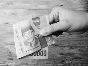 Close-up of cropped hand holding paper currency at table