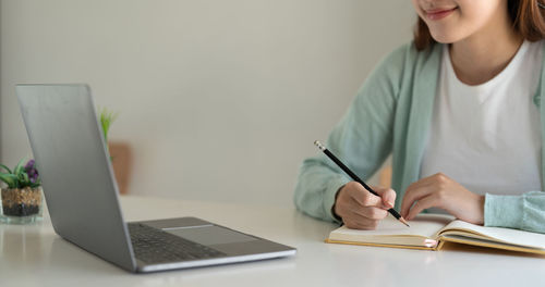 Midsection of woman using laptop on table