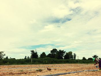 Scenic view of field against cloudy sky