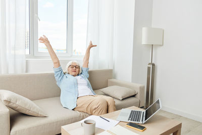 Young woman using digital tablet while sitting on bed at home