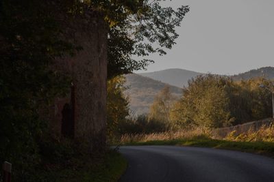 Road by trees against sky