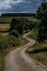 Road amidst field against sky