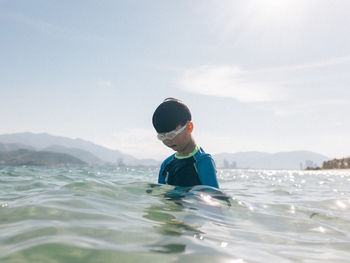 Boy in sea against sky