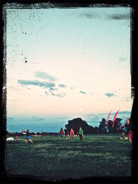 People on field against cloudy sky