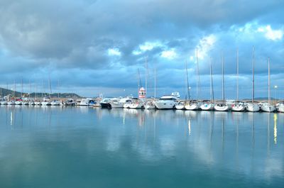 Boats moored at harbor against sky