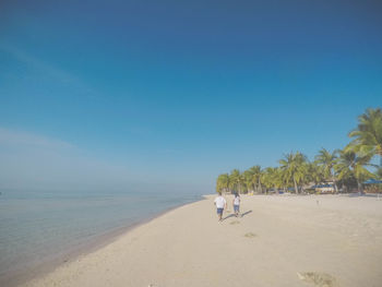 Scenic view of beach against clear blue sky