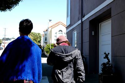 Rear view of people walking against buildings in city