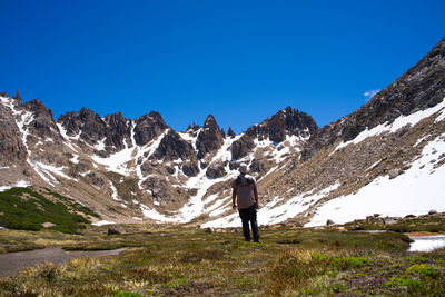 Rear view of man standing on mountain against sky