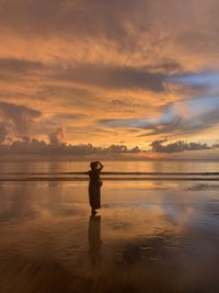 Man standing on beach against sky during sunset