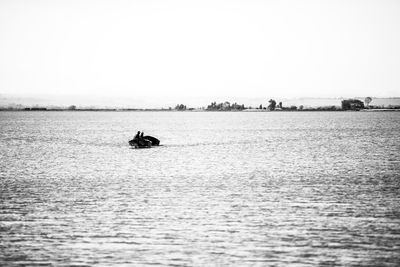 Person on boat in sea against sky