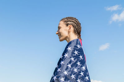 Low angle portrait of woman against blue sky