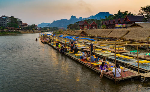 Boats moored on river by buildings against sky