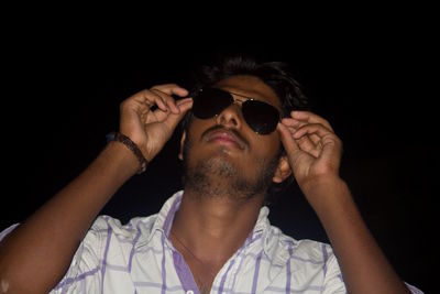 Young man wearing sunglasses against black background