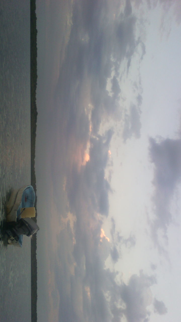 LOW SECTION OF MAN STANDING AGAINST CLOUDS