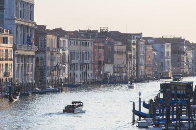 Boats in canal by buildings against sky in city