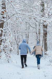 Rear view of man walking on snow