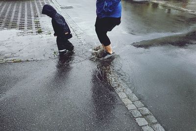 Low section of people walking on wet road during rainy season