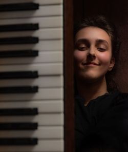 Portrait of smiling woman near piano keys