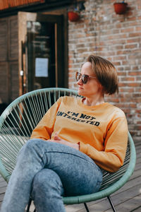 Beautiful young woman with short blond hair in casual clothing sitting and smiling.