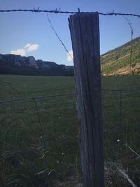Fence on grassy field against sky
