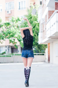 Rear view of woman standing against building in city