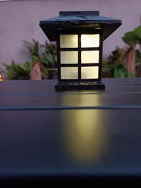 Close-up of illuminated lamp on table against building