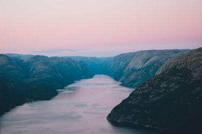 Scenic view of sea by mountains against sky during sunset