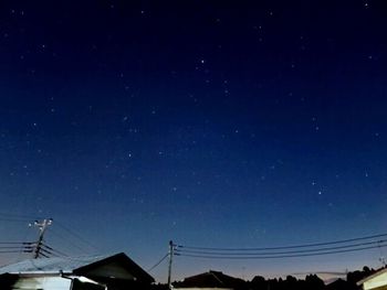 Low angle view of silhouette electricity pylon against sky at night