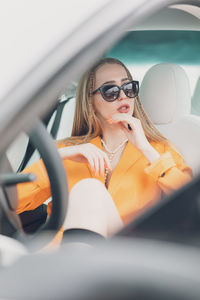 Side view of young woman sitting on side-view mirror